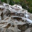 Искусственный каскадный водопад с двумя изливами, изготовлен и установлен в городе Сочи для ландшафтного дизайна территории размером 6,5 на 5 метров из полимер бетона.